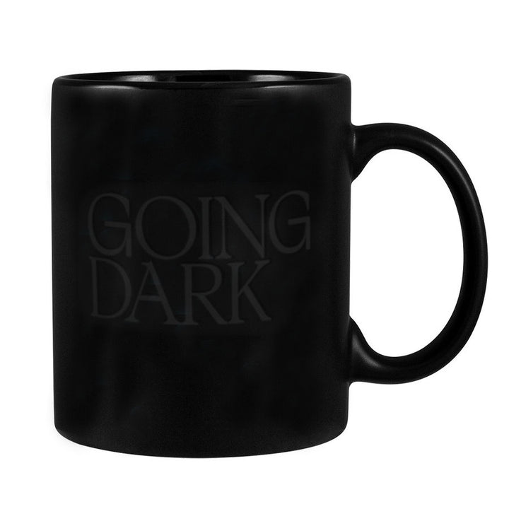 The Going Dark Color Changing Mug is a matte black stoneware mug with "GOING DARK" subtly printed in glossy letters. It features a smooth finish and large, rounded handle for style and practicality.