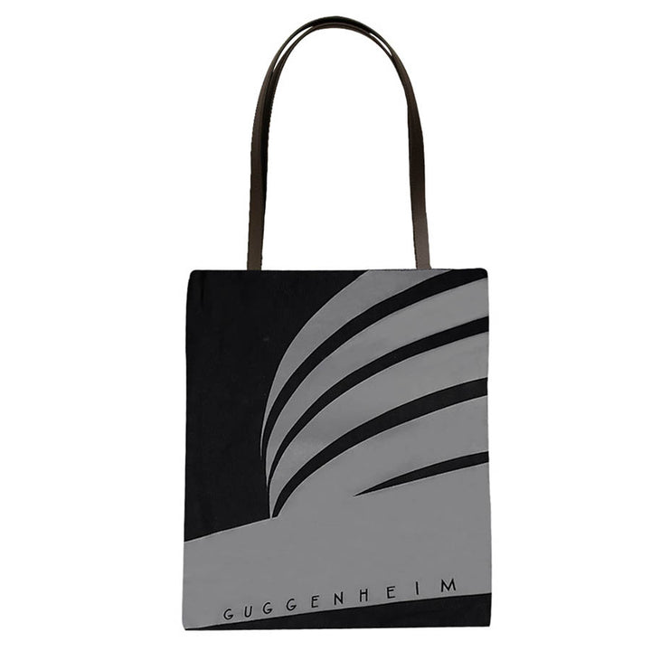 The Guggenheim "Go Dark" Tote is a black and gray limited edition bag with a minimalist illustration of the museum’s curved architecture and “GUGGENHEIM” printed at the bottom.