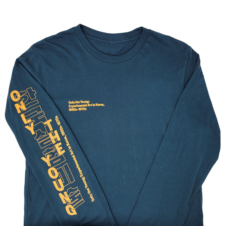 A teal long-sleeve "Only the Young: Experimental Art in Korea, 1960s-1970s" T-shirt featuring yellow chest text and bold yellow Korean and English exhibition merchandise text on the right sleeve.