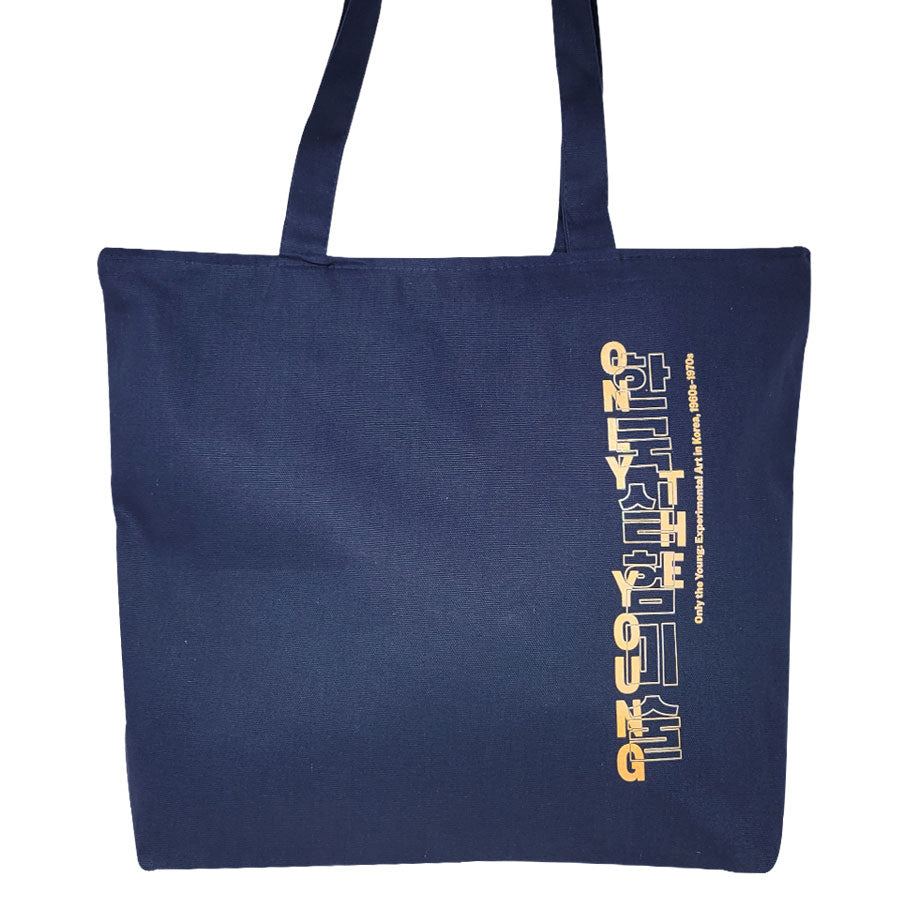 The Only the Young: Experimental Art in Korea, 1960s-1970s Exhibition Tote is a navy blue heavy-duty cotton bag with long handles and vertical yellow and white text reading STAY YOUNG on one side.
