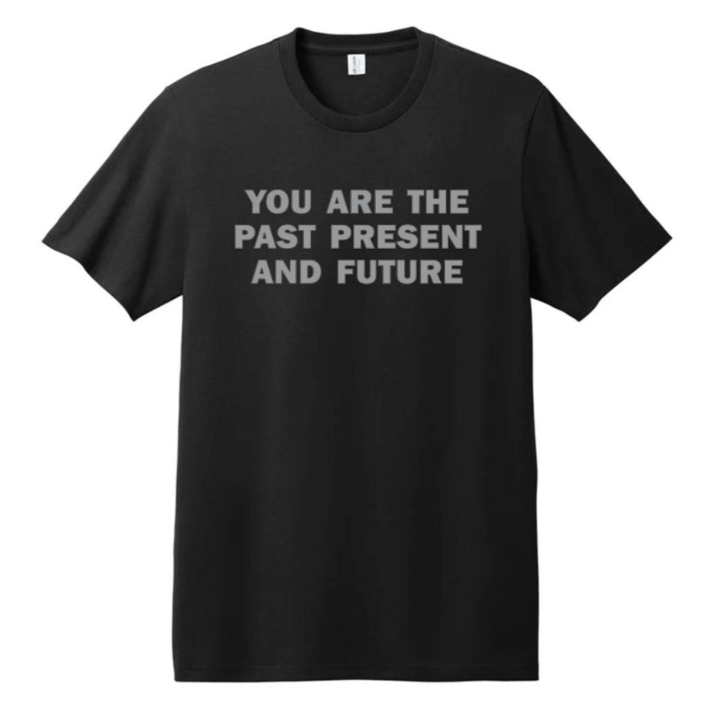 The Jenny Holzer T-Shirt is a black unisex tee made from recycled cotton, featuring bold gray text on the front that says, YOU ARE THE PAST PRESENT AND FUTURE.