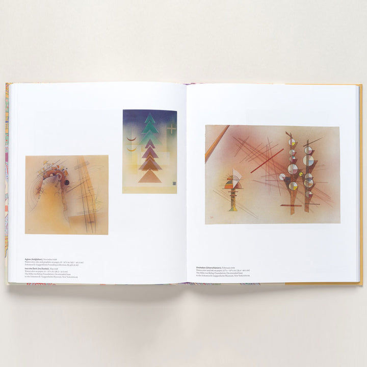 An open copy of "Vasily Kandinsky: Around the Circle" displays abstract Bauhaus-inspired artwork with geometric shapes, lines, and soft gradients. Each page shows two pieces, including two vertical, tree-like abstract compositions on the right.