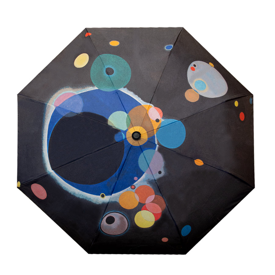 A black Kandinsky Umbrella, Several Circles, viewed from above features a colorful abstract pattern of overlapping blue, orange, yellow, and red circles—reminiscent of art at the Guggenheim Museum.