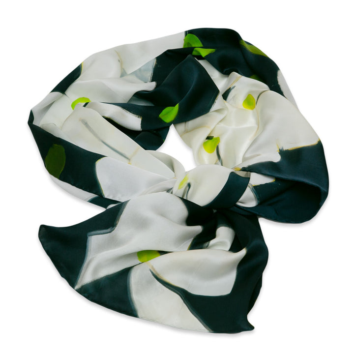 The Alex Katz Dogwood Silk Scarf, featuring white and dark green floral patterns with bright green accents, is inspired by the elegance of the Guggenheim Museum and displayed in a circular shape on a white background.