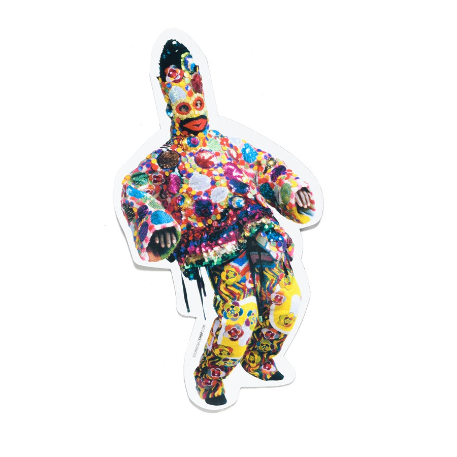 A person wearing a vibrant costume inspired by the Nick Cave Magnet Sequined stands against a white background, covered in bright flowers, sequins, beads, and a striking headpiece with mask—turning fashion into sculptural art.